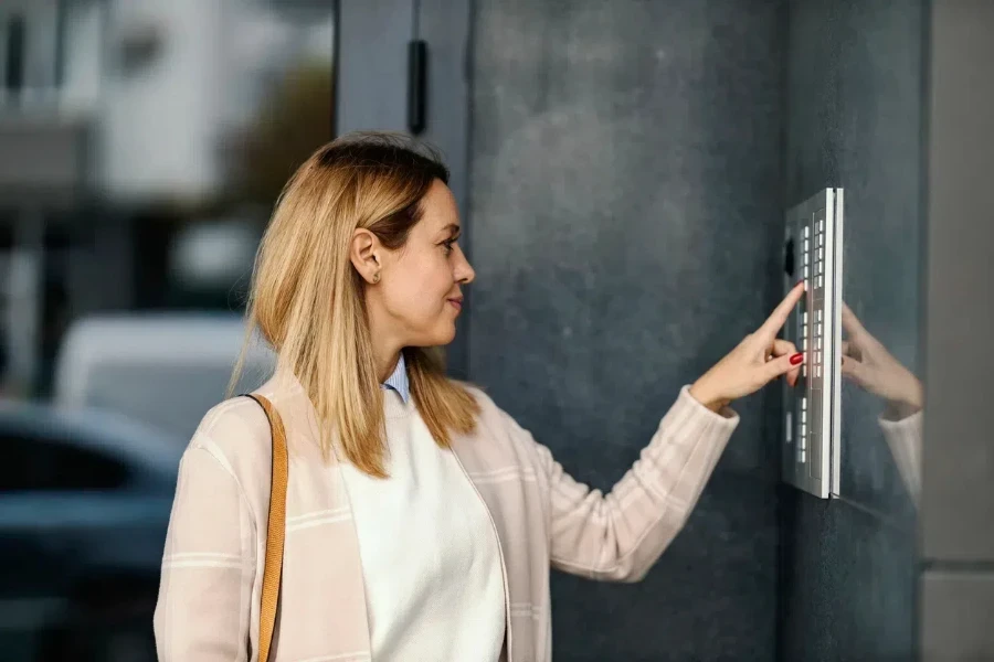 Uma mulher de meia idade está chamando o interfone de um prédio no centro da cidade