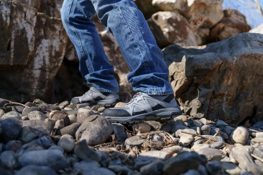 A person wearing jeans and sneakers walking on rocks