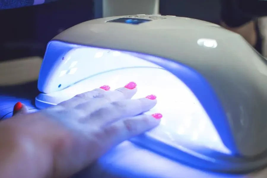 A woman puts her hand under a UV nail lamp