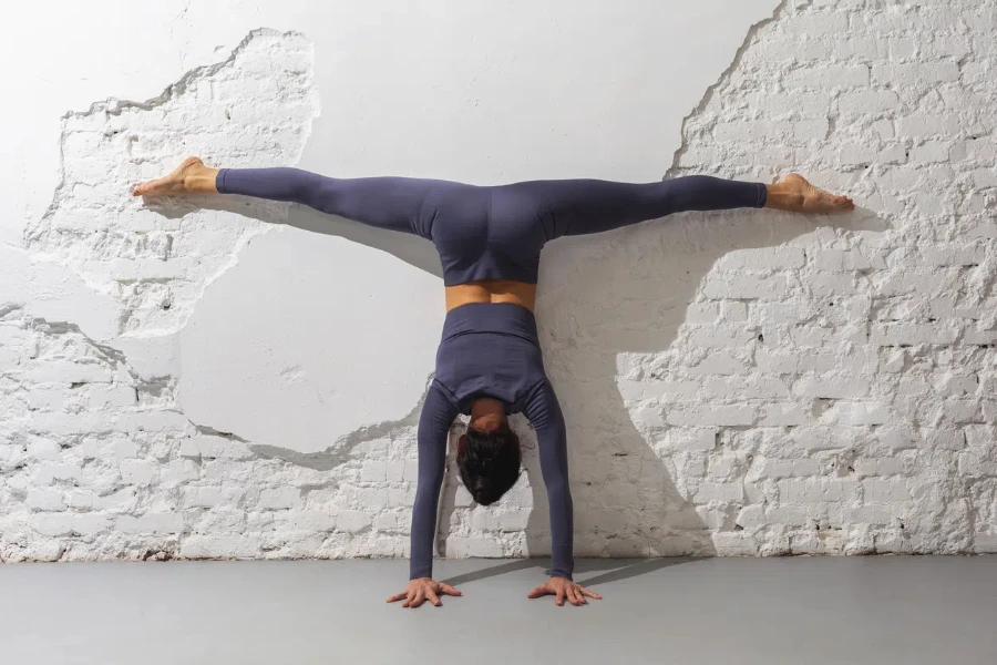 Un'istruttrice che pratica yoga esegue l'esercizio Adho Mukha Vrikshasana contro il muro