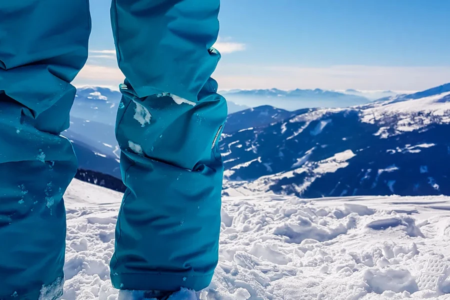 Ноги женщины в синих лыжных брюках, стоящей на вершине Качберга в Австрии.