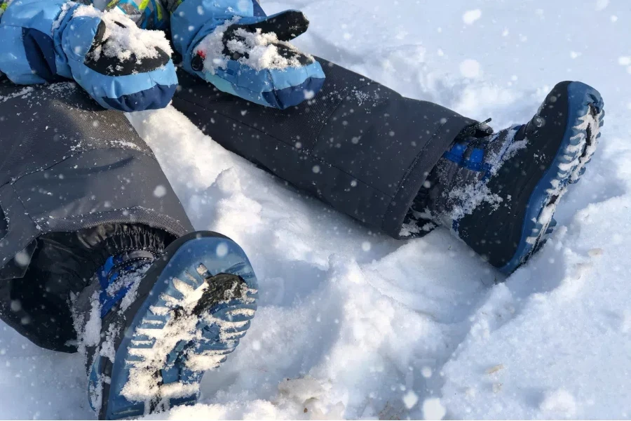 防寒着を着た少年が手袋の中に雪を抱えている。大雪の後に撮った写真