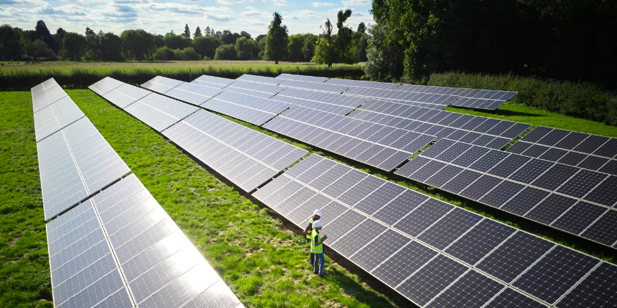 Foto aérea de drone de engenheiros inspecionando painéis solares em campo gerando energia renovável