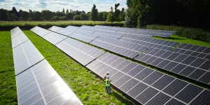 Снимок с дрона инженеров, проверяющих солнечные панели в полевых условиях, генерирующих возобновляемую энергию