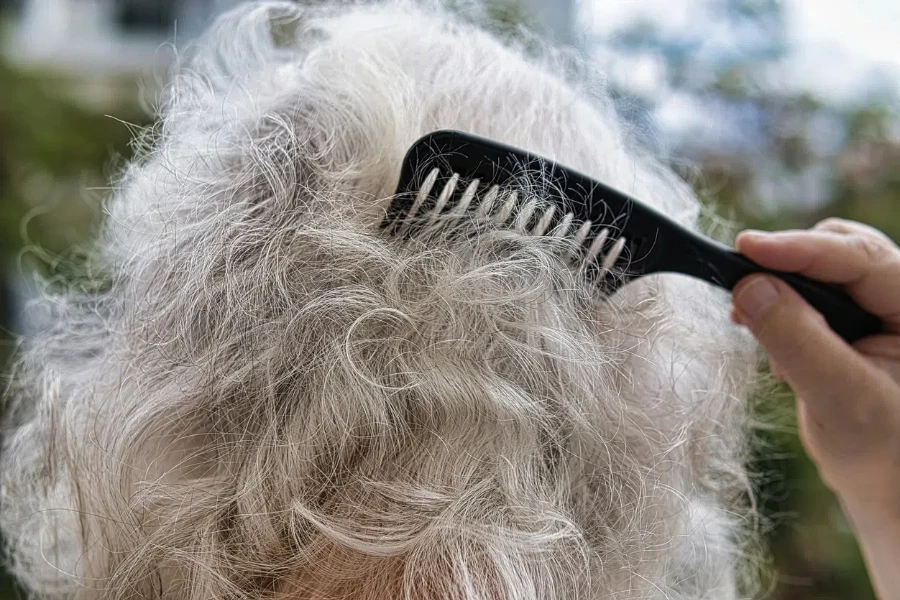 Una signora anziana che si pettina i capelli grigi e ricci