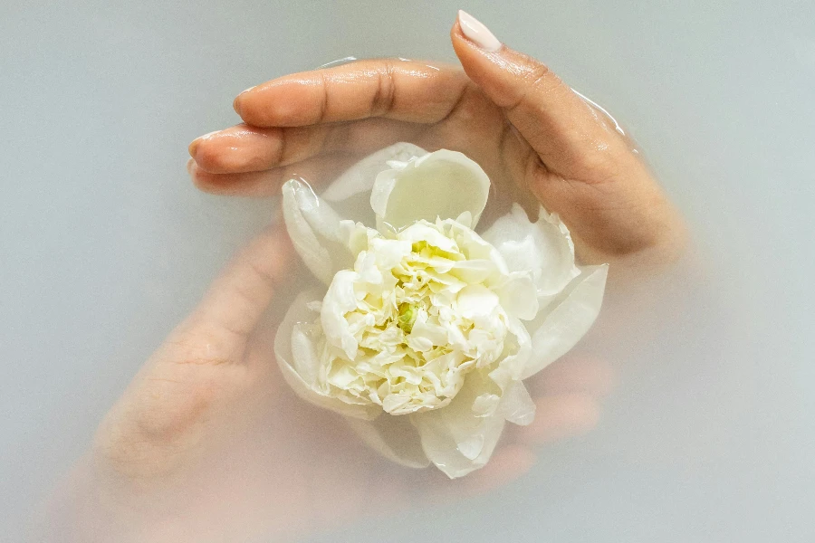 Anonymous woman with gentle white flower in water