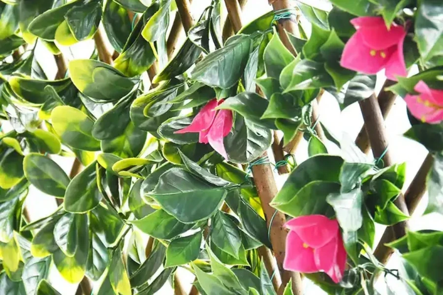 Artificial green leaves and pink flowers in vertical fence panels