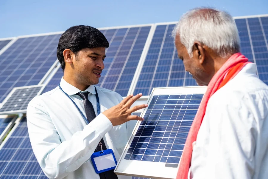 Banquero o ingeniero explicando a los agricultores sobre los paneles solares o el uso de la energía para su uso en el campo agrícola: concepto de estilo de vida sostenible