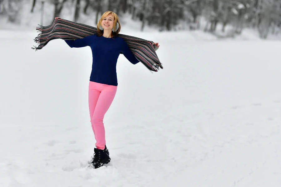 Belle femme debout dans la neige avec les bras tendus tenant un châle