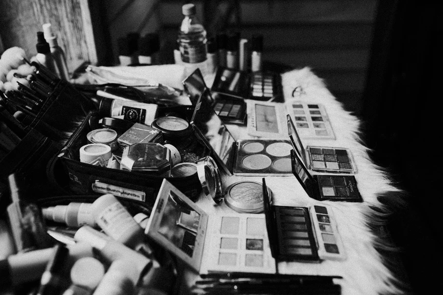 assorted makeup products and tools placed on dressing table near mirror