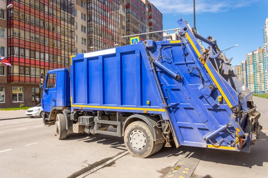 Blue garbage truck takes out household waste in a densely populated residential area of the city