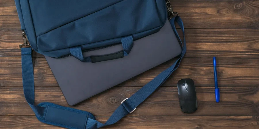 Stylo bleu, souris et ordinateur portable avec un sac sur fond en bois