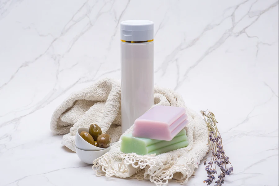 Flasche mit Waschmittel, Seife, Handtuch und Lavendelpflanze auf einer Marmorplatte