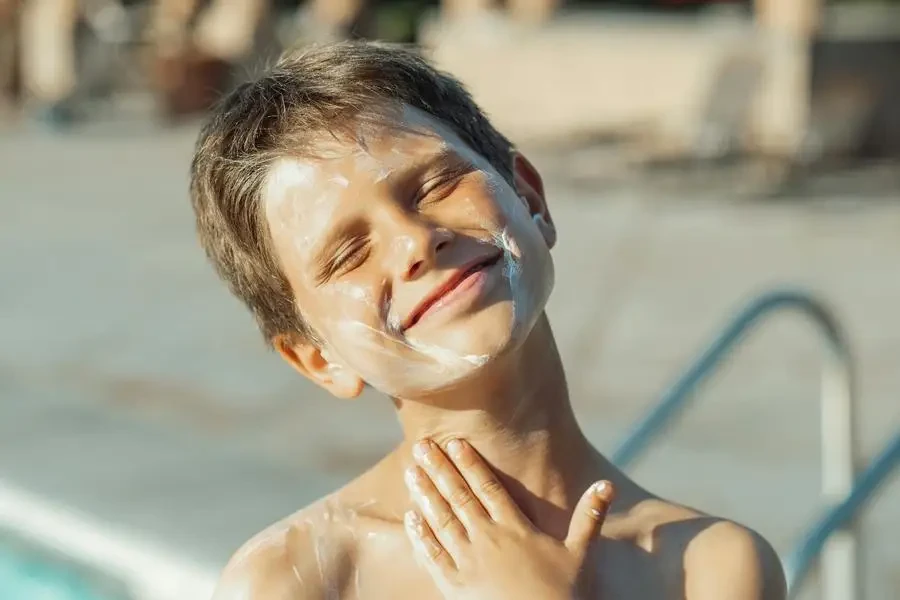 Boy Applying Sunscreen Lotion on His neck by Kindel Media