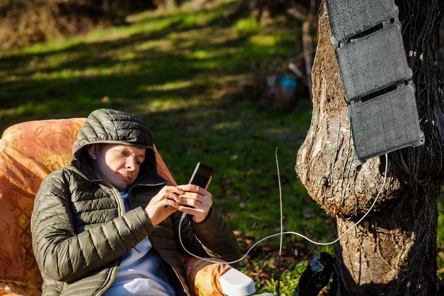 Camper carga su teléfono con una batería solar portátil