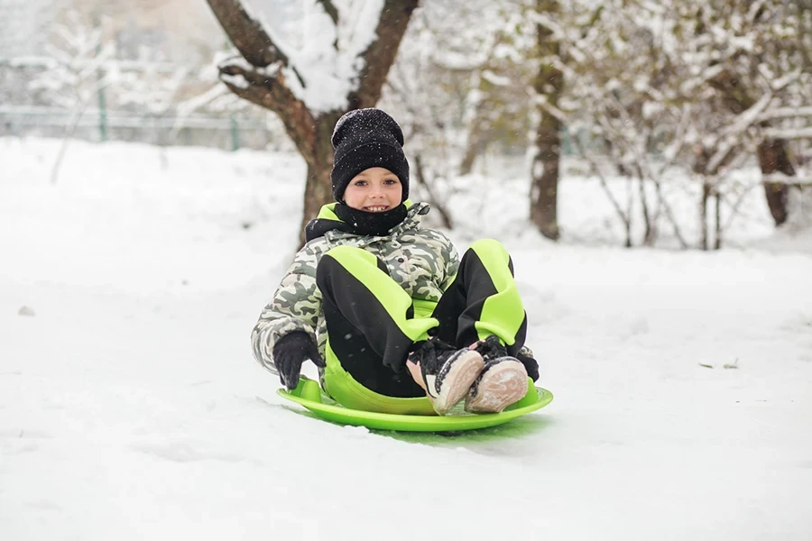 Criança menina passeio na placa de neve