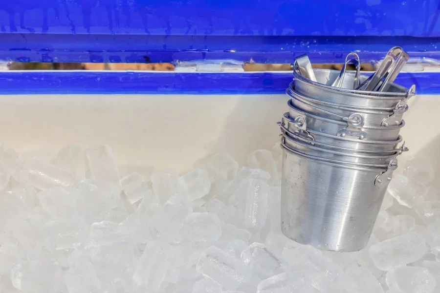 Cubos de gelo transparentes são mantidos em grandes tanques de plástico e pequenos baldes de metal prontos para servir no restaurante