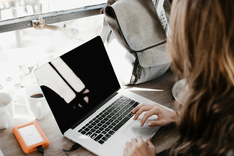 Close-up Photography of Woman Sitting Beside Table While Using Macbook