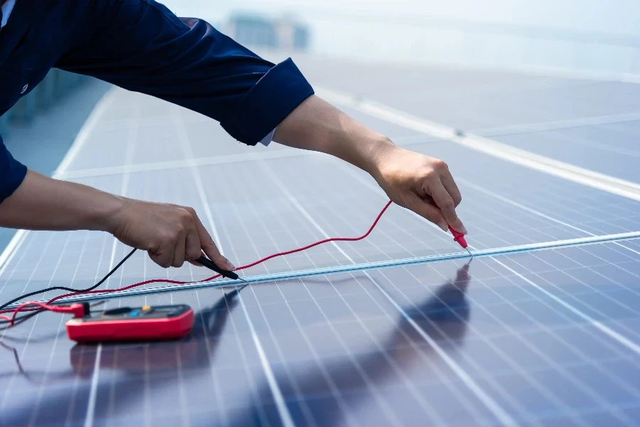 As mãos fechadas dos engenheiros estão usando instrumentos de medição elétricos no plano da célula solar