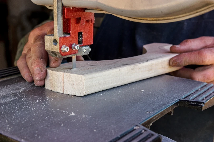 Close-up worker hands in the carpentry workshop cuts the log into boards using band saw