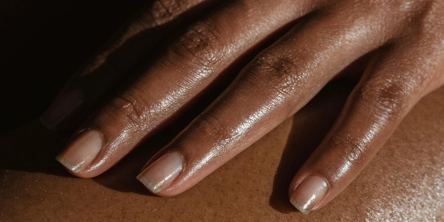 African American female touching bare leg with hand while sitting on black background