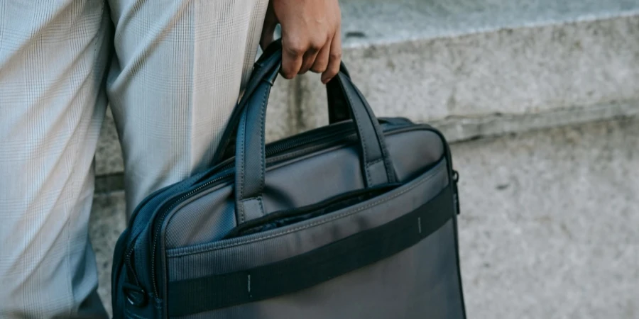 Crop entrepreneur with laptop in bag