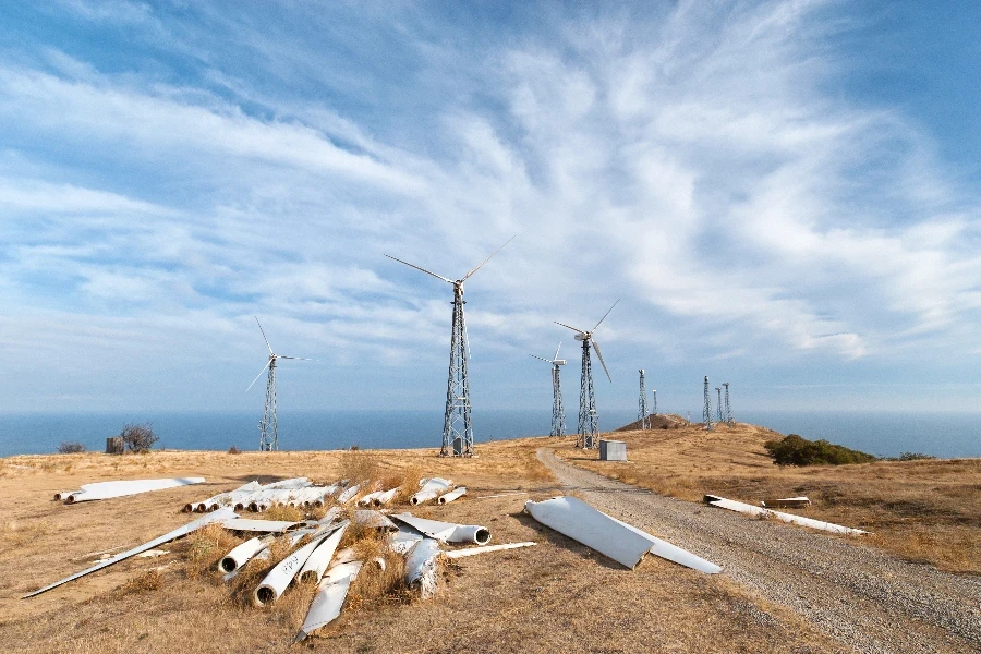 Centrale éolienne délabrée avec des pièces de rechange d'éoliennes au premier plan