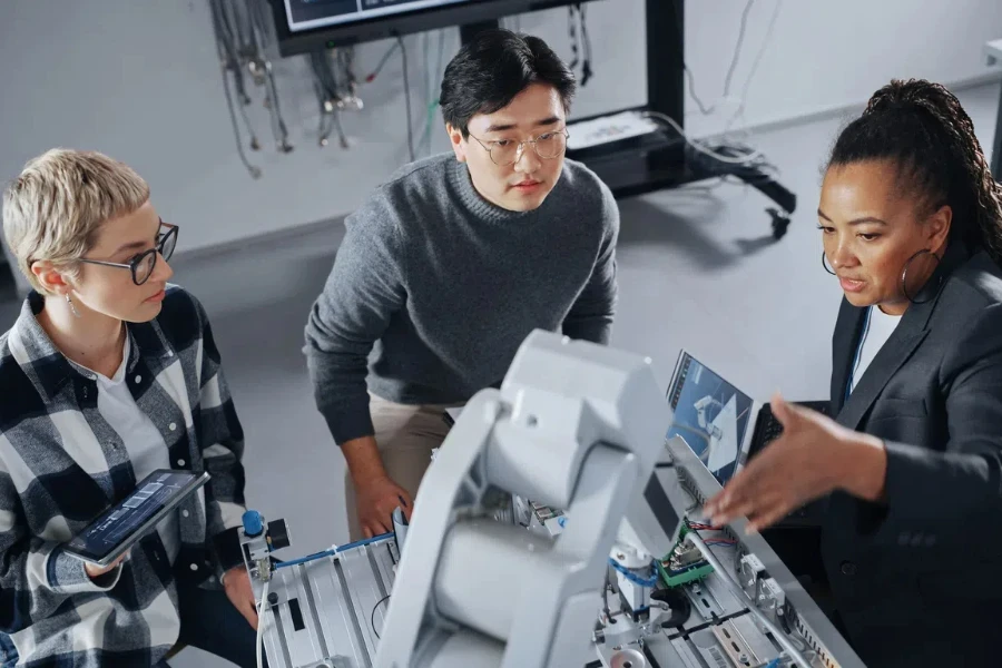 Diverse Students and Black Teacher Looking at Robot Hand and Discussing