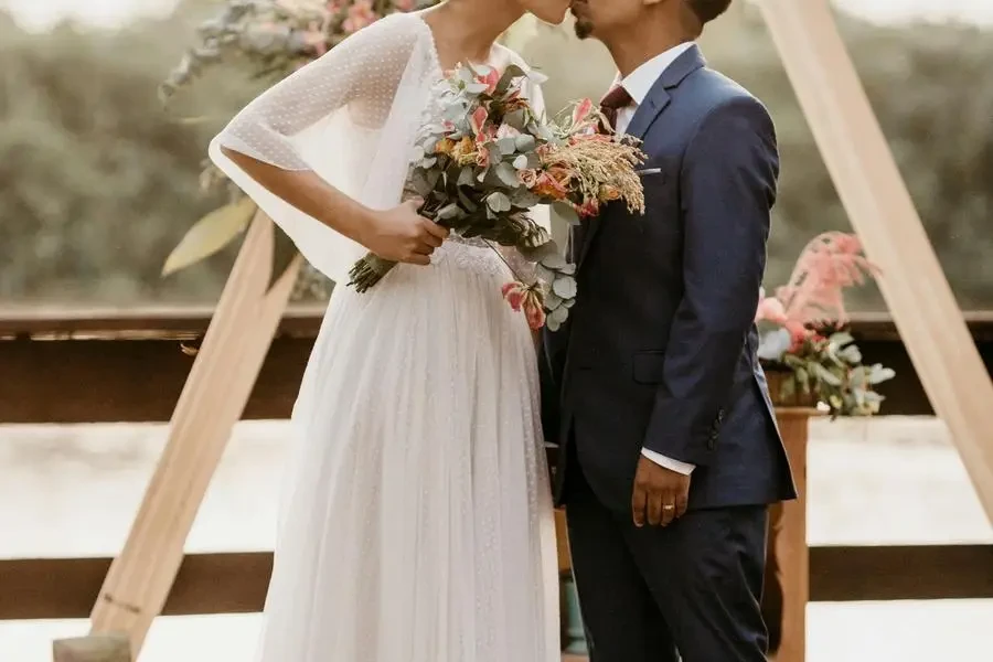 Diverse newlywed couple kissing on wooden terrace by Jonathan Borba