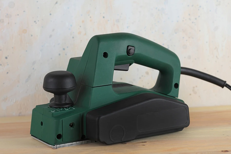 Electric planer on wooden table and against the background of a plastered wall