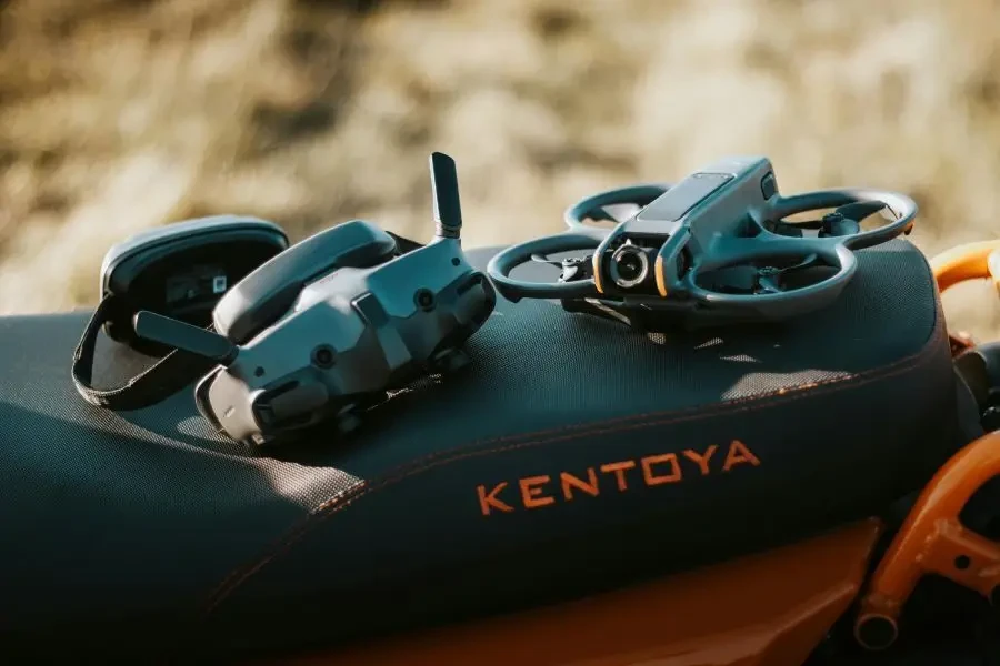 FPV drone and goggles placed on a motorcycle seat with Kentoya visible, showcasing outdoor tech setup