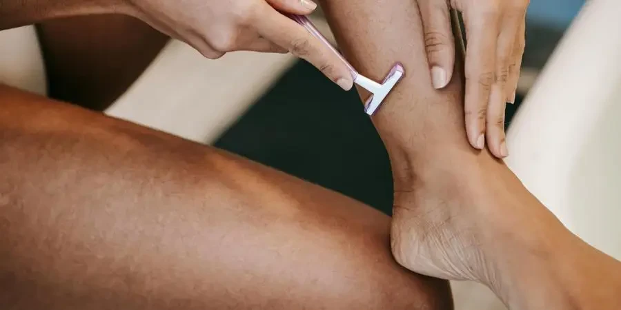 Faceless ethnic woman depilating leg with razor in bathroom by Sora Shimazaki