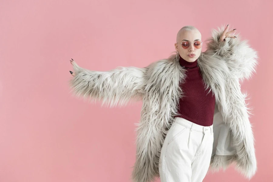 Femme à la mode en manteau de fourrure dansant en studio