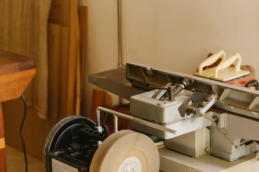 Grinder near wooden planks in light workshop by Ono Kosuki