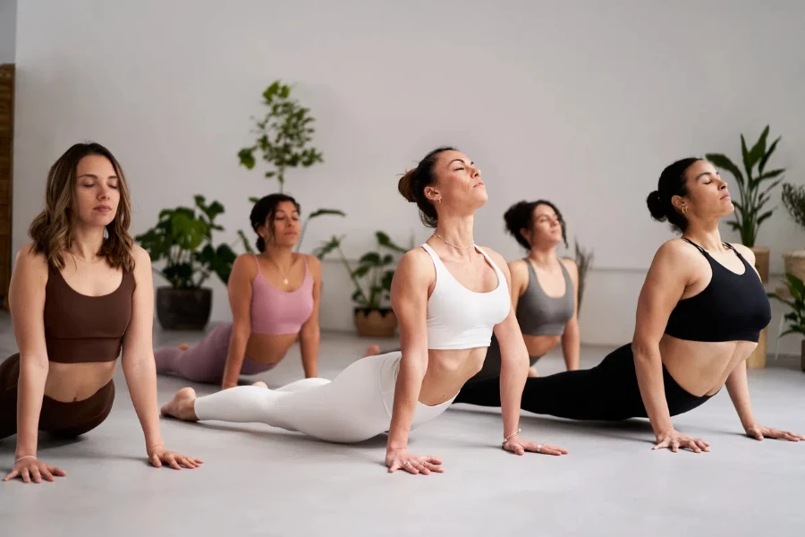 Group of women in a yoga class practicing downward-facing dog pose inside studio. Wellness and mindfulness healthcare concept