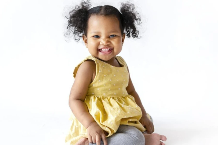 Bayi perempuan yang bahagia mengenakan gaun kuning yang hangat dan cerah