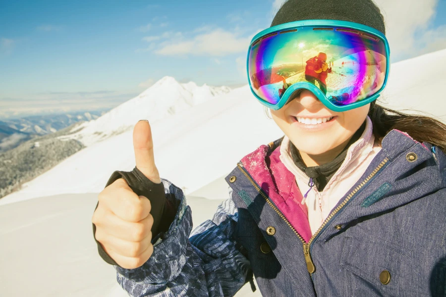 Счастливая девушка, одетая в модные очки для катания на лыжах или сноуборде