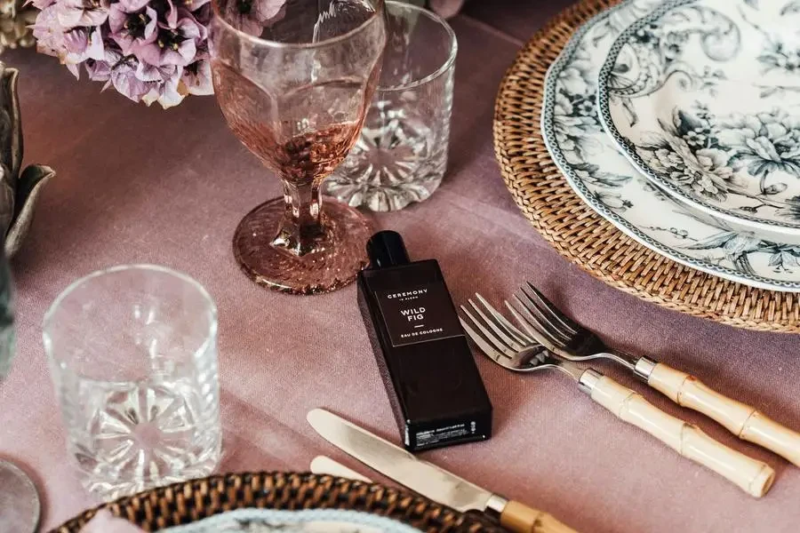 Ángulo alto de una elegante mesa de banquete decorada con un ramo de flores colocado cerca de una botella de perfume de furkanfdemir