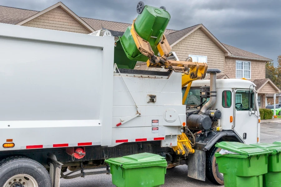 Horizontal shot of the mechanical arm on a modern trash truck dumping garbage without help