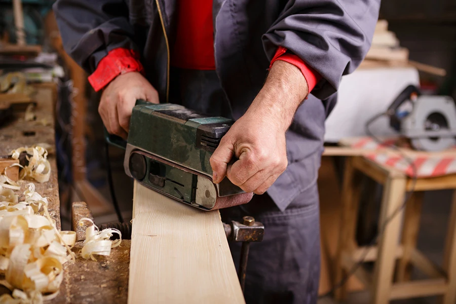 Joiner with a belt sander on a wooden board with sawdust