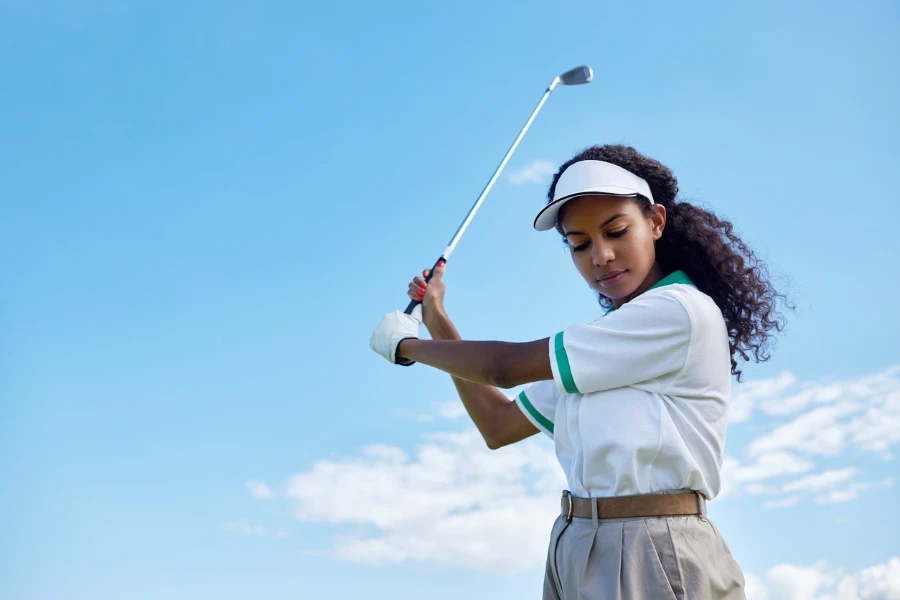 Low Angle Portrait einer jungen schwarzen Frau beim Golfspielen