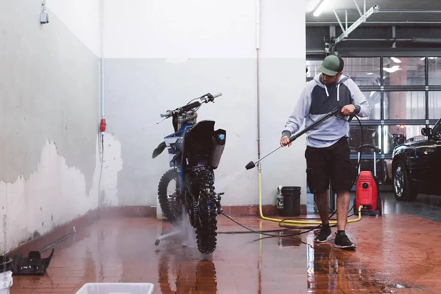 Hombre limpia su bicicleta de motocross con un limpiador a presión