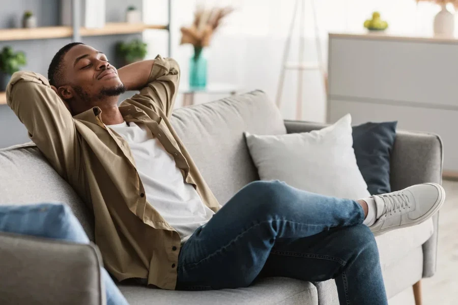 Man Enjoying Lazy Weekend In Living Room.