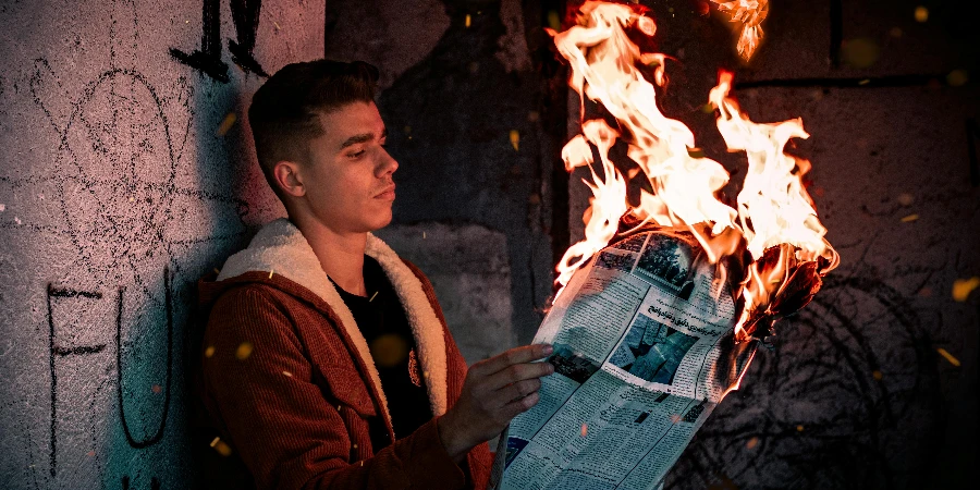 燃える新聞を持っている男性