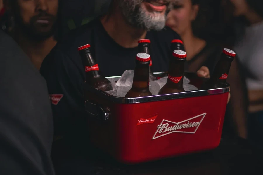 Hombre sujetando un recipiente lleno de hielo y botellas de cerveza