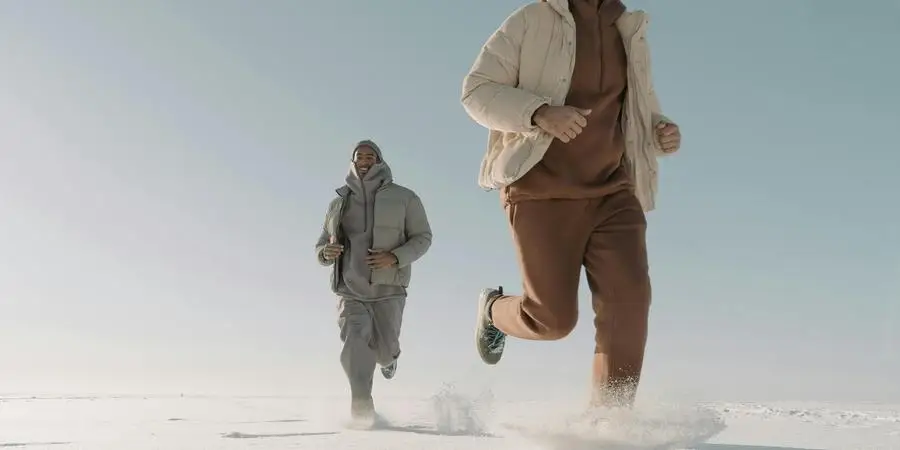 Uomo che indossa piumini che corre sulla neve spessa di cottonbro studio