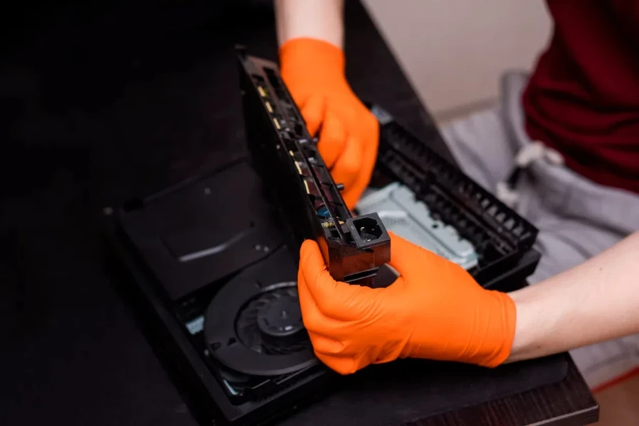 Man in orange gloves parses the PlayStation 4 Pro console