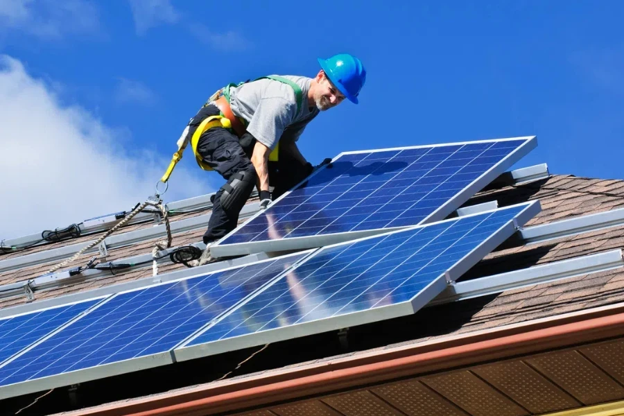 Hombre instalando paneles solares fotovoltaicos de energía alternativa en el techo