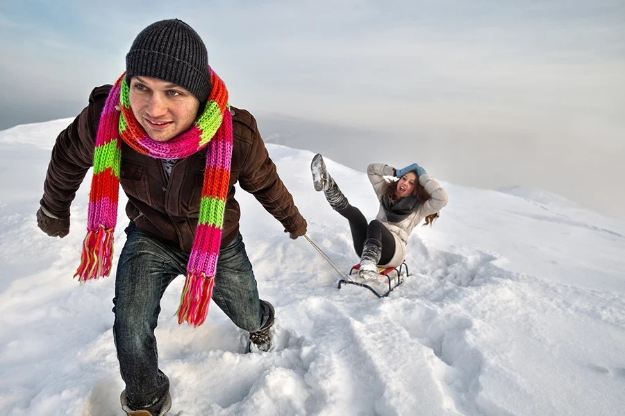 Uomo che tira una ragazza su una slitta sulla neve