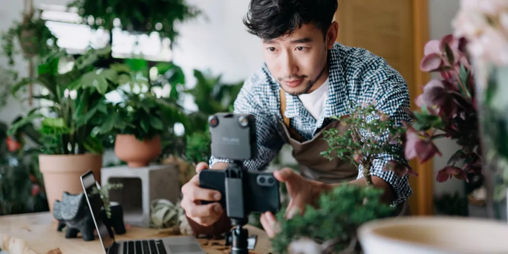 植物のビデオを撮るためにカメラをセットしている男性